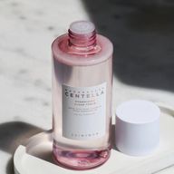 بطری شفاف تونر با رنگ صورتی و برچسب سفید که روی آن نوشته شده "MADAGASCAR CENTELLA POREMIZING CLEAR TONER" و "SKIN1004". درپوش بطری جدا شده و در سمت راست آن قرار دارد.